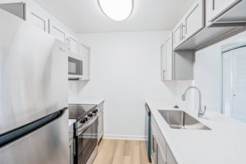 A modern kitchen with stainless steel appliances and white countertops.
